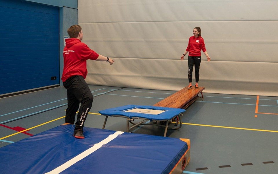 Student PMOOS geeft instructies aan medestudent voor sprong op trampoline.