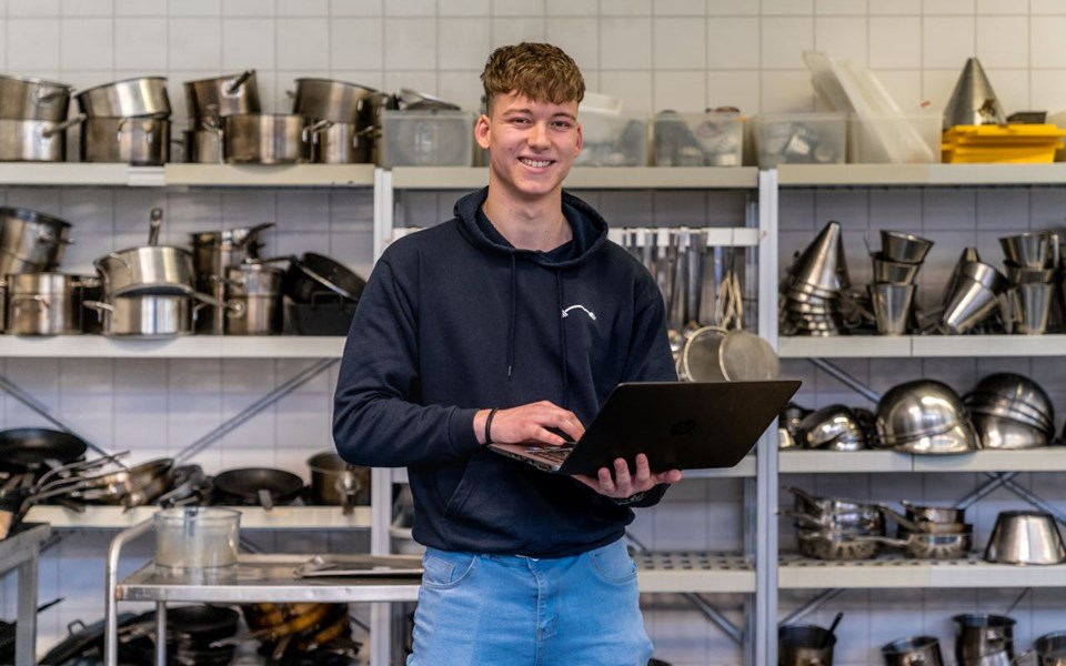 Student e-commerce specialist lacht in camera met laptop in hand