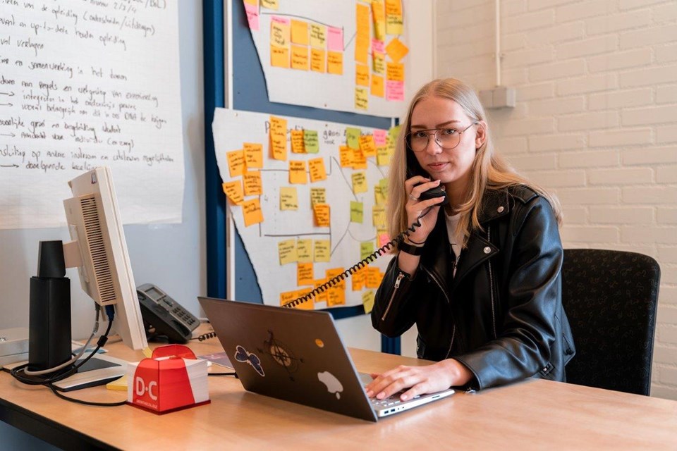 ICT Niveau 3 4 Iris Sijbom 2022 (19) ICT-er in opleiding belt met vaste telefoon achter laptop