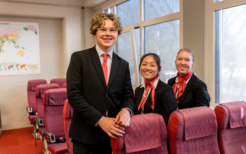 Student Luchtvaartdienstverlener poseren bij vliegtuigstoelen