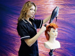 Studente haarstylist is haar van pop aan het föhnen