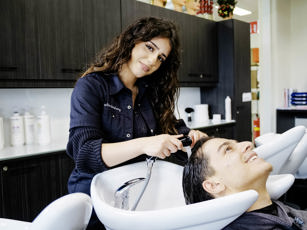 Studente haarstylist is haren aan het wassen tijdens de les