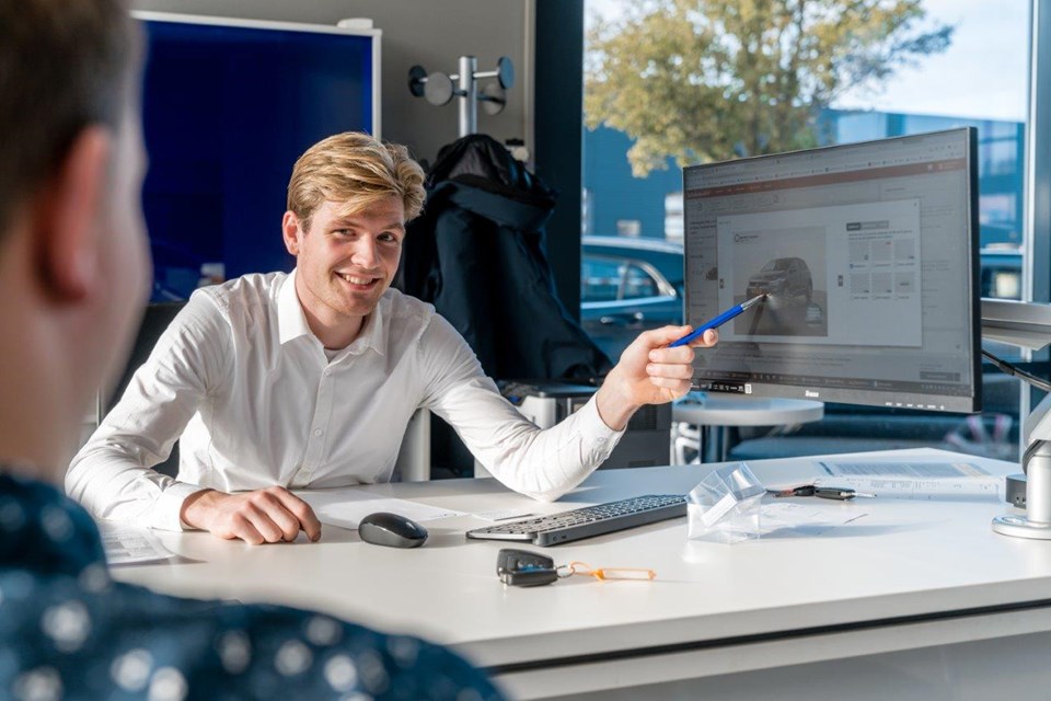 Man wijst klant auto aan op computerscherm.