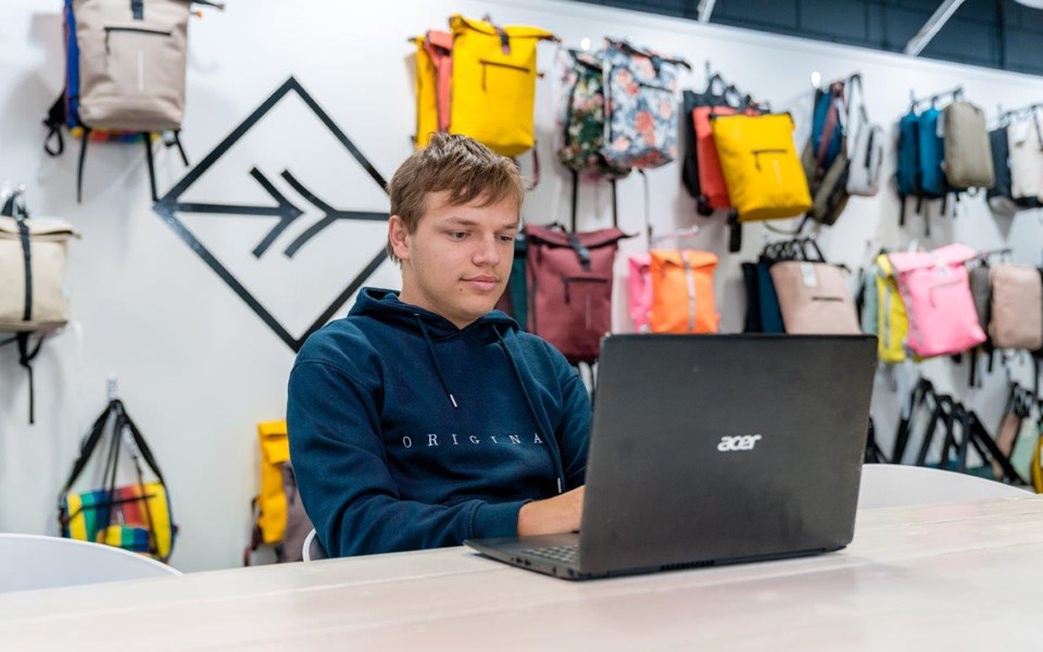 Jongens werkt achter computer in tassenwinkel. 