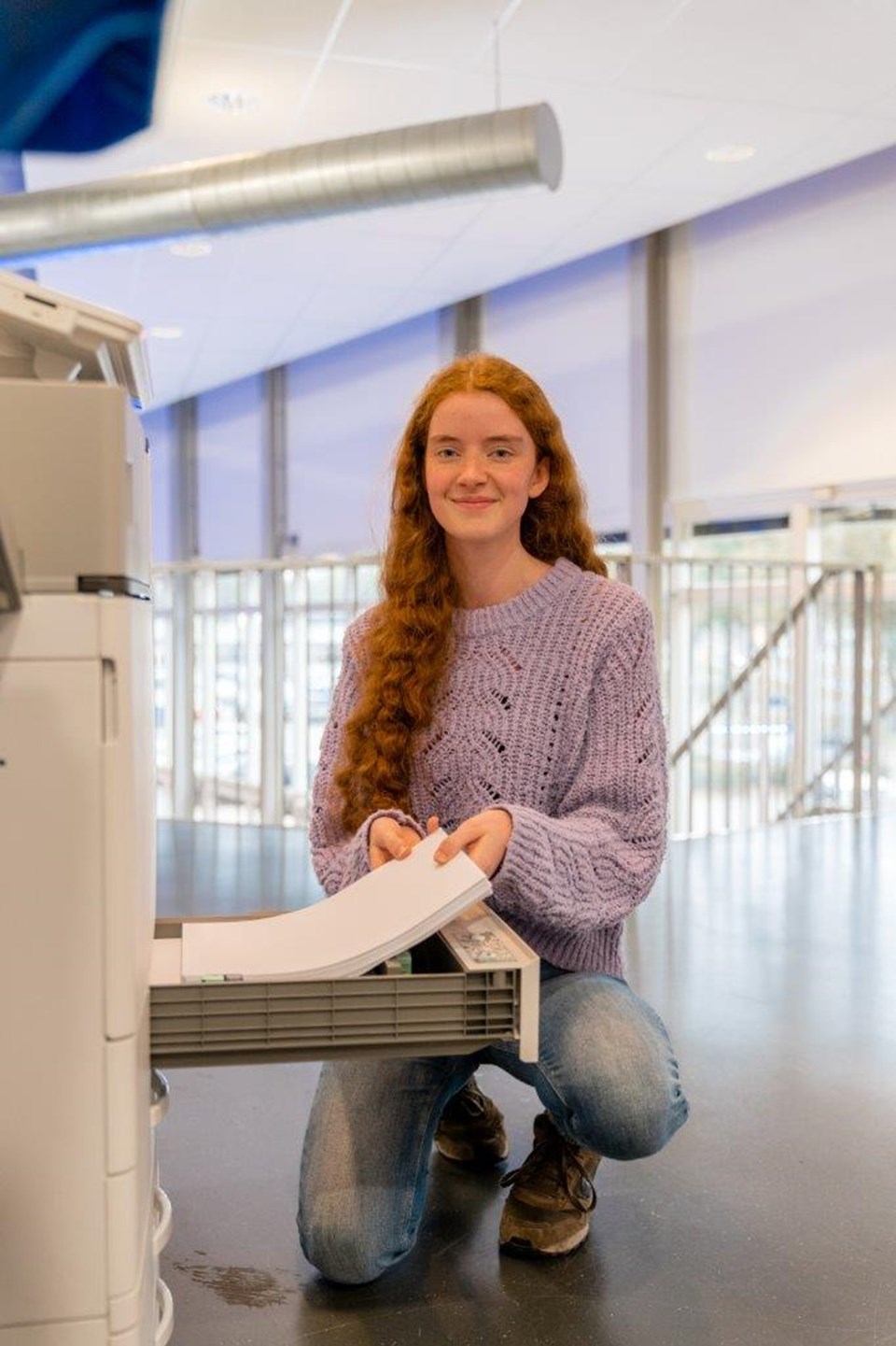 Student Facilitair vult papier aan in kopieerapparaat