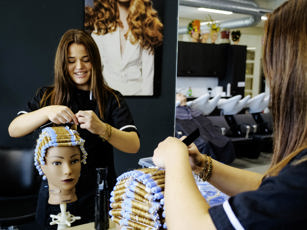 Studente haarstylist oefent met rollers zetten