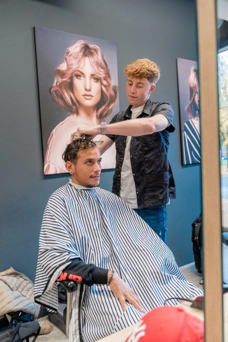 Student kapper kamt haar van man in stoel.