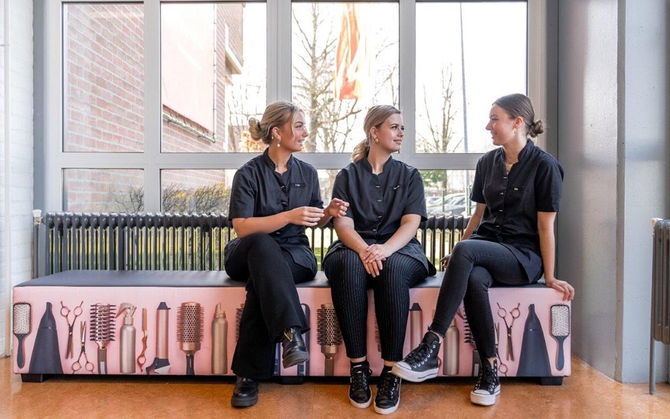 Drie studenten schoonheidsverzorging zitten op een bank en praten met elkaar