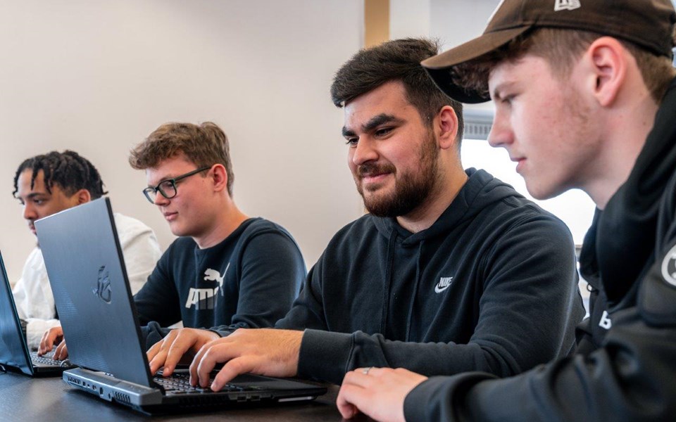 Vier studenten Software Developer werken achter laptop