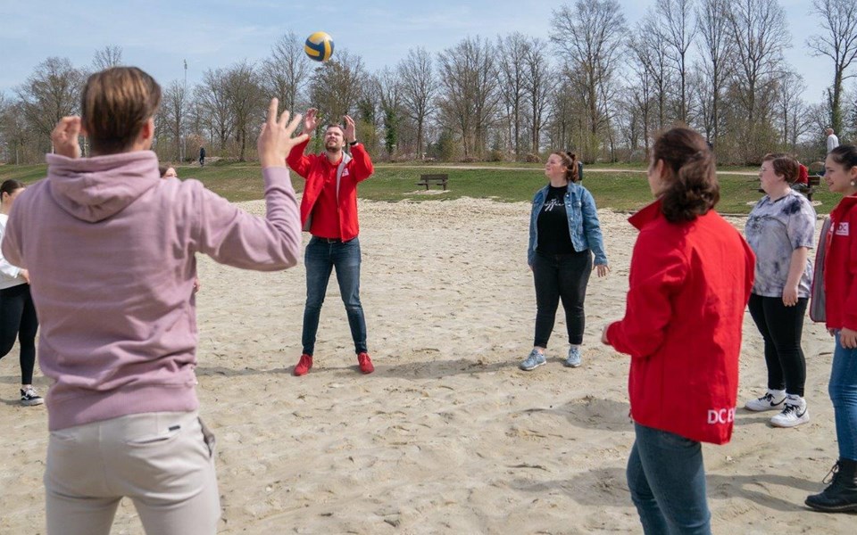 Studenten spelen volleybal op een strand