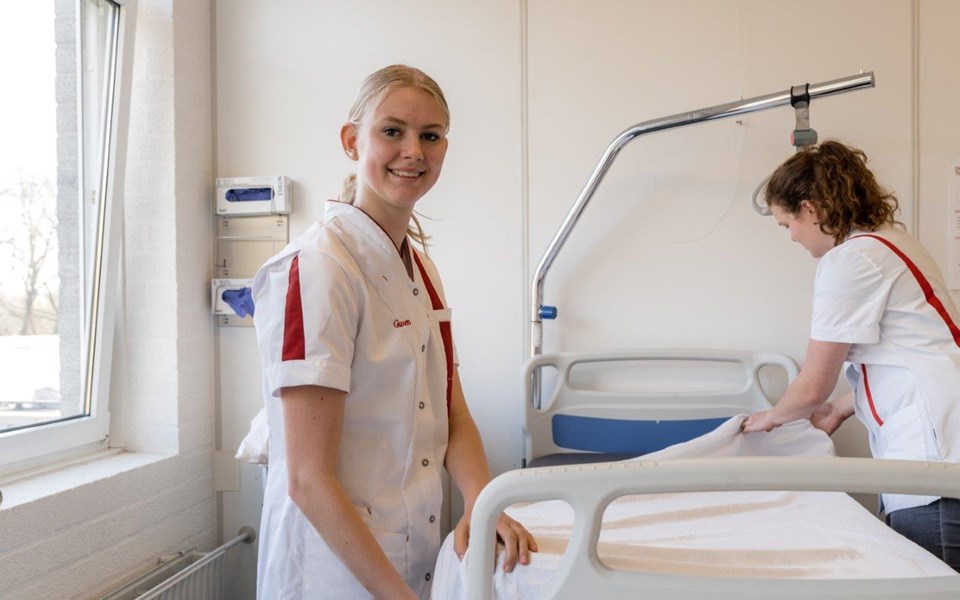 Twee studenten verpleegkunde maken bed op. 