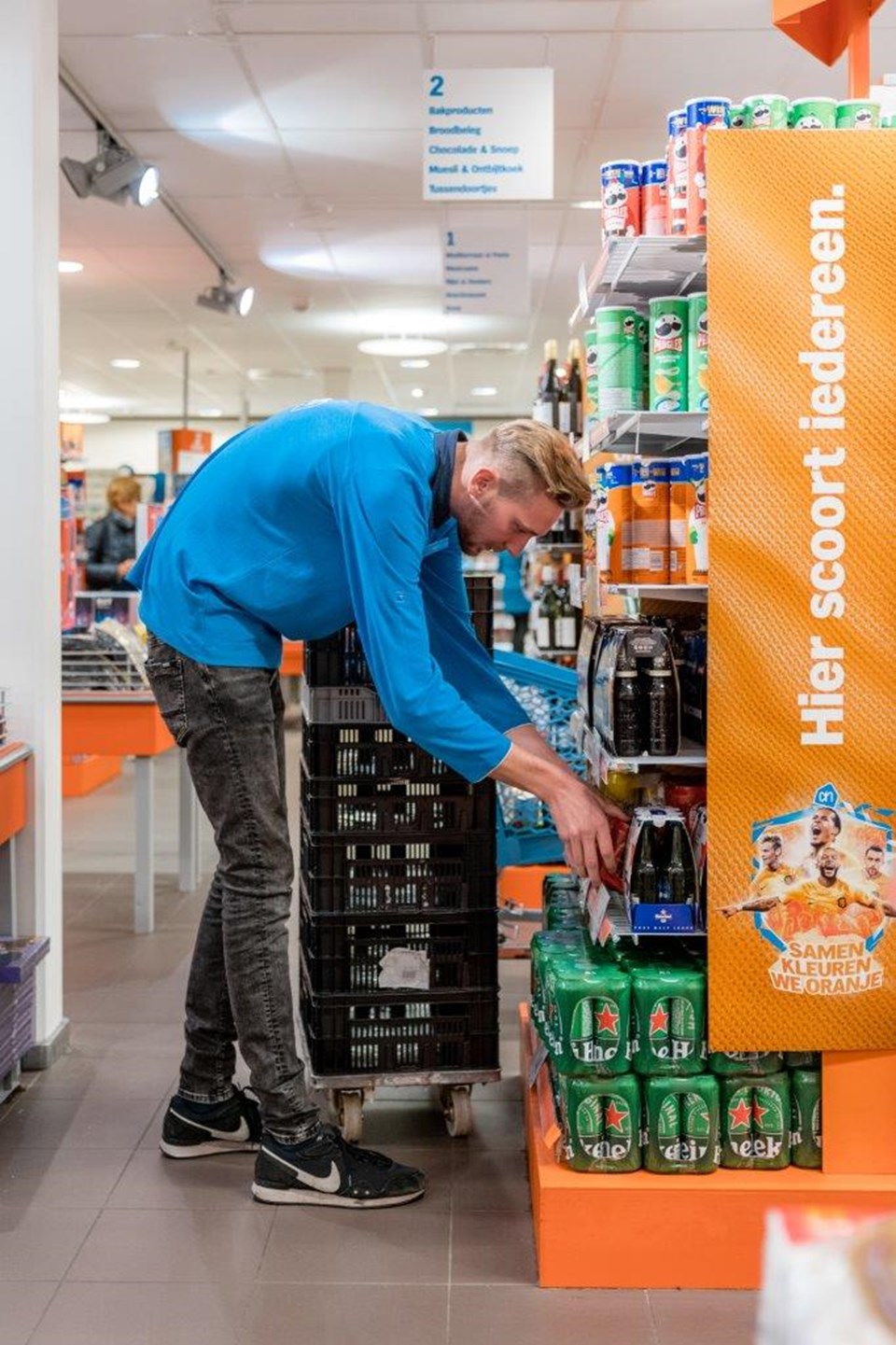 Man in supermarkt zet drinken in het schap.