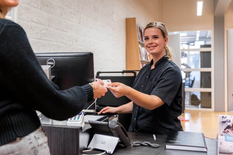 Schoonheidsverzorging + Salon, Iris Sijbom 2022 (5) Schoonheidsspecialist staat achter de balie en geeft wisselgeld aan klant