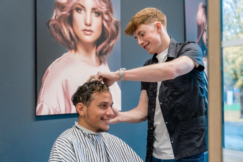 Kapper scheert zijkant haar van man in stoel