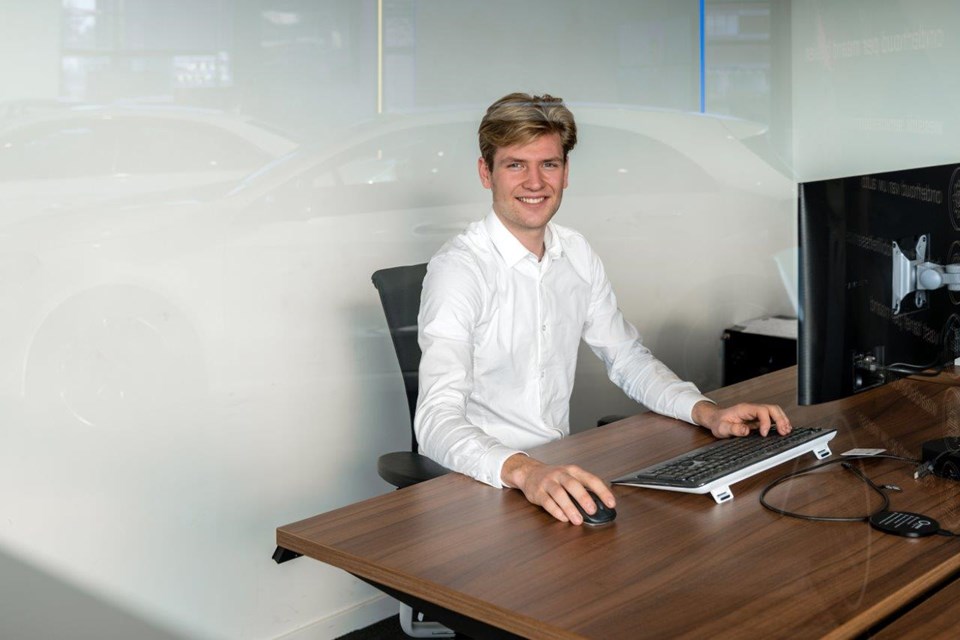 Man zit in witte blouse achter computer op kantoor.