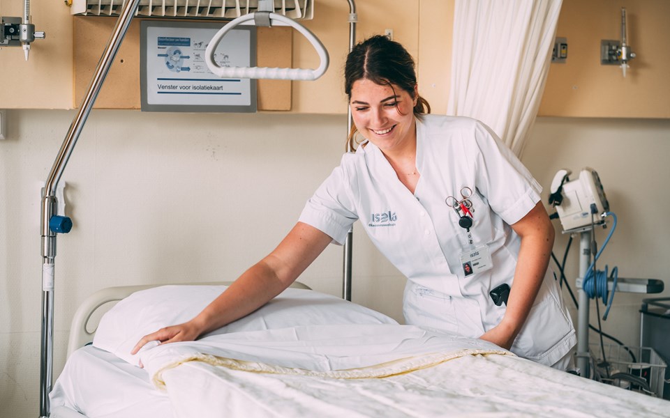 Student verpleegkunde maakt bed op in ziekenhuis