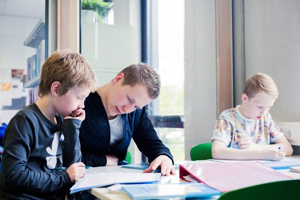 Begeleiden met school Begeleider helpt kind met huiswerk