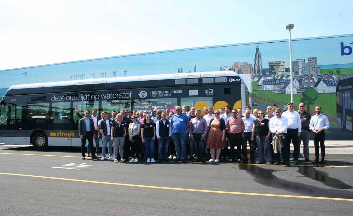 Groepsfoto bij bus die rijdt op waterstof