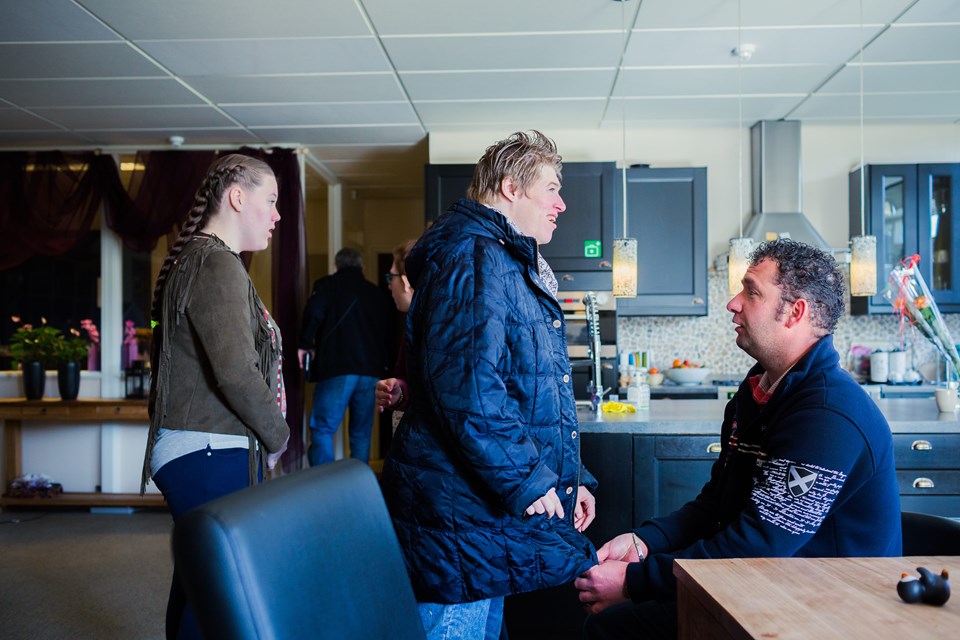 Begeleiden bij wonen Verzorger helpt cliënt jas aan doen