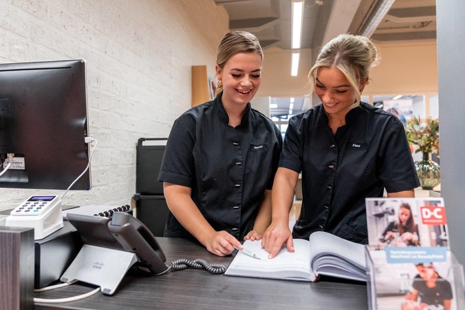 Schoonheidsverzorging + Salon, Iris Sijbom 2022 (20) Twee studenten schoonheidsverzorging praten met elkaar achter de balie en kijken in de agenda