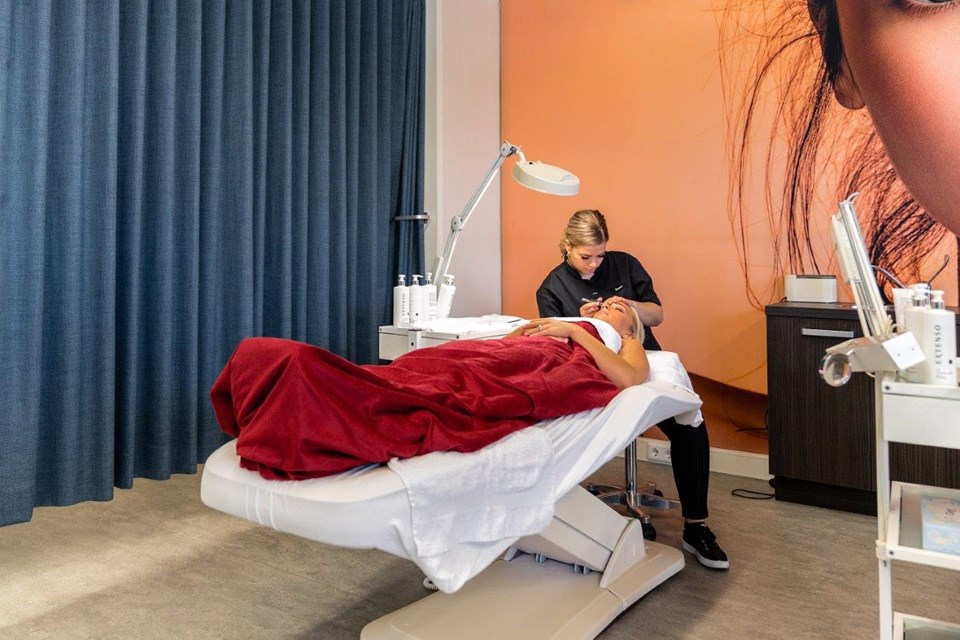 Schoonheidsverzorging + Salon, Iris Sijbom 2022 (14) Schoonheidsspecialist in opleiding zit op kruk en epileert wenkbrauwen klant