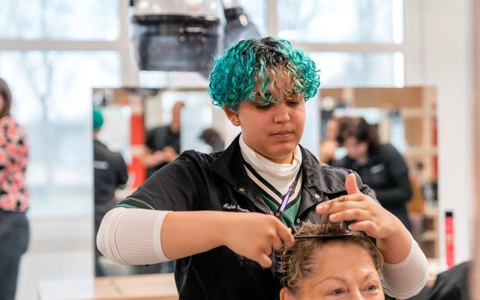 Student kapper houdt haar klant omhoog om te knippen