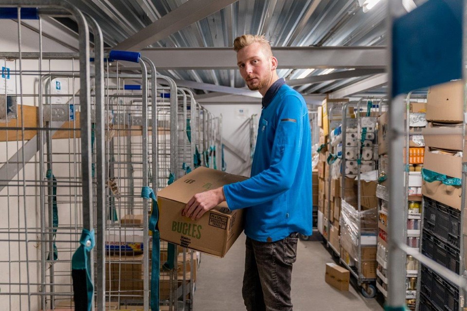Man zet dozen in magazijn supermarkt.