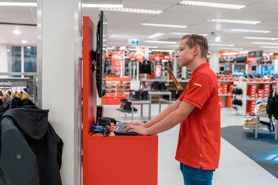 Jongens zoekt in winkel iets op in computer.
