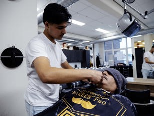 Student barbier aan het oefenen met snor trimmen tijdens de les