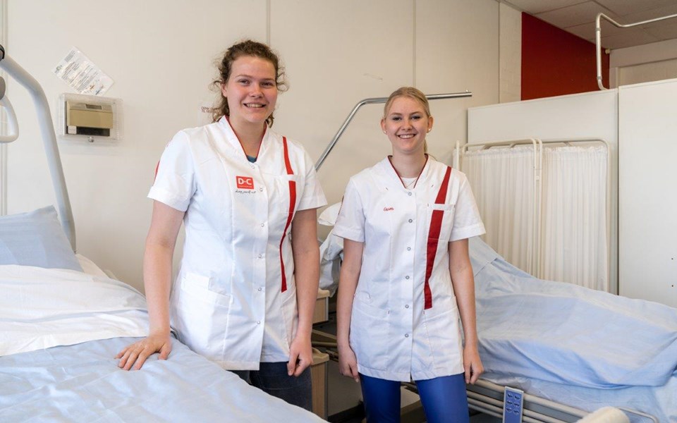 Twee studenten Verpleegkundige staan tussen twee bedden. 