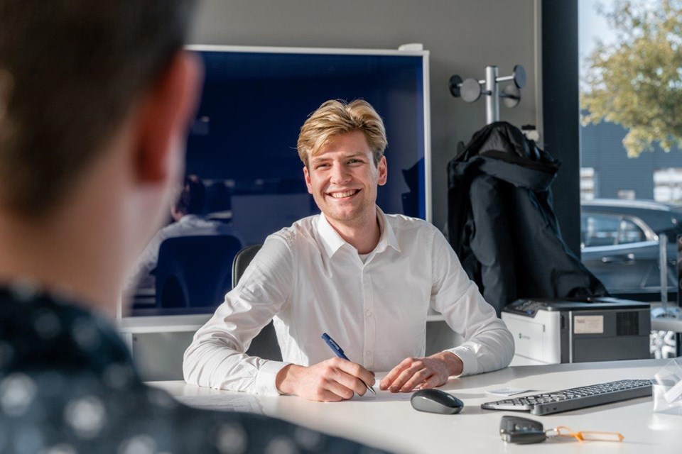 Man zit met klant in kantoor en schrijft iets op.