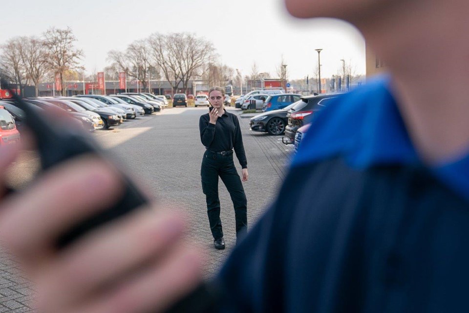 Studente beveiliging op parkeerplaats met portofoon