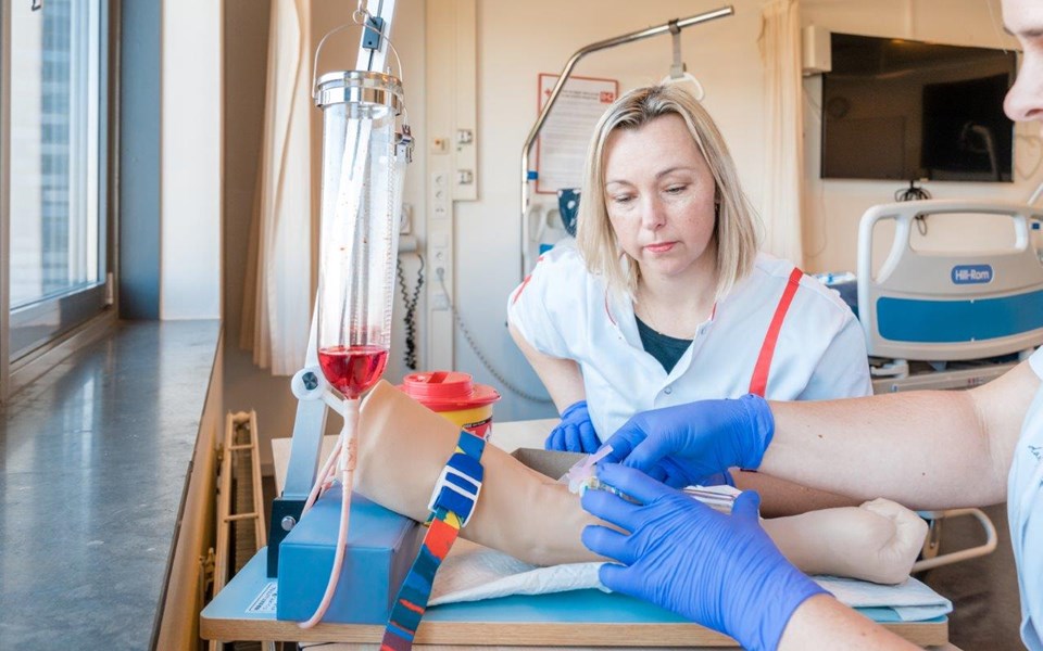 Twee verpleegkundigen oefenen bloedprikken op kunstarm