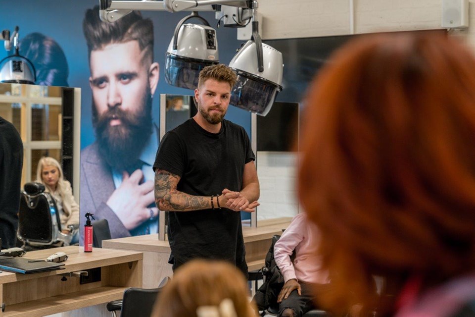 Student Salonmanager staat middenin salon met collega's om zich heen.