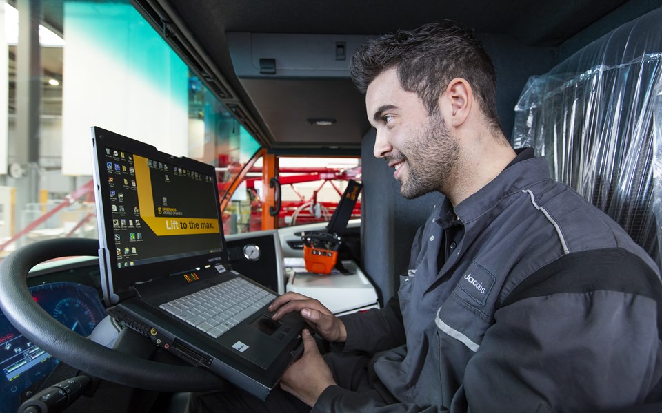 Monteur in vrachtwagen werkend op laptop