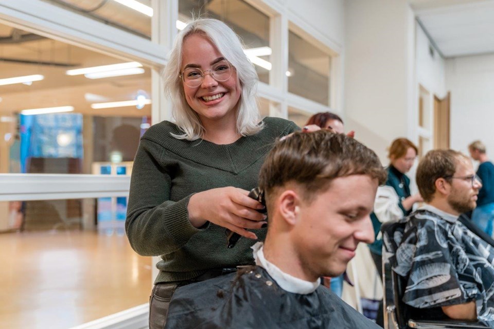 Kapster scheert achterkant hoofd van man in stoel.