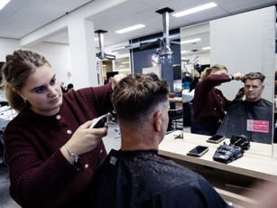 Studente barbier en klant voor de spiegel